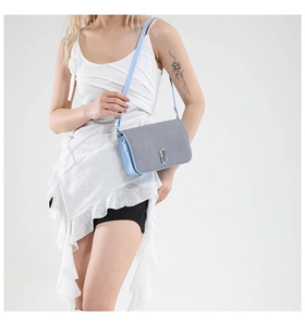 Detail of silver interlocking logo and grey glitter flap on blue crossbody bag