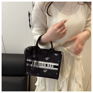 Detail of black tote with white rose embroidery and elegant lace bow handle decoration