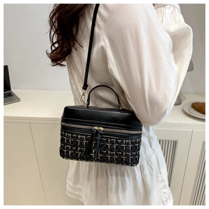 Close-up of black leather and tweed plaid crossbody box bag worn by a model