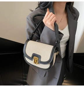 Detail of canvas saddle bag featuring black PU leather trim and contrast stitching