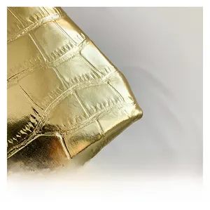 Detailed macro view of golden faux crocodile leather texture with metallic glossy finish