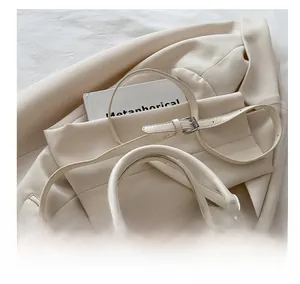 Detail of cream white faux leather bag with adjustable strap and silver metal hardware
