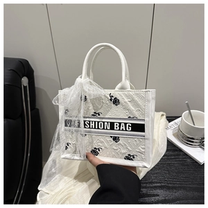 Detailed close-up of white lace tote bag with black rose embroidery and bow accent