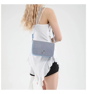Detail view of a compact contrast color crossbody bag with silver buckle on a model