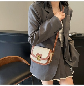 Model wearing a retro canvas saddle bag with leather trim and gold buckle closure