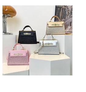 Detail of glittery mini Kelly bags in pink, black, silver and gold with gold twist locks