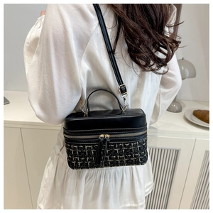 Détail du sac boîte bandoulière en tweed et cuir porté par un mannequin en intérieur