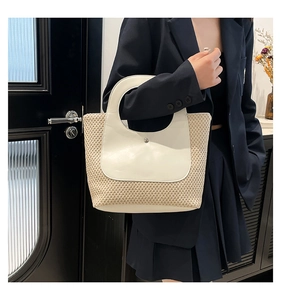 Detail of summer straw woven handbag featuring cream leather trim and round cutout handle