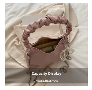 Pink pleated crescent bag interior showing spacious storage with phone and pearl charm