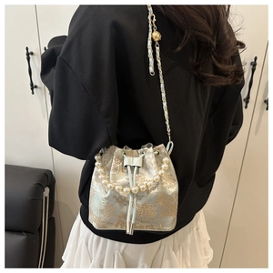 Detail of embroidered jacquard bucket bag with pearl handle and chain strap on shoulder
