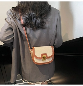 Retro canvas saddle bag with brown leather trim and golden clasp shown on shoulder