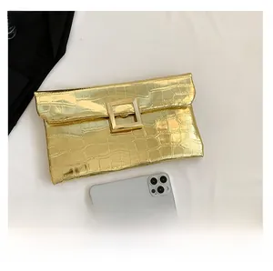 Detail of gold faux crocodile leather clutch with a large square metal buckle and mirror finish