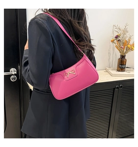 Detail of rose pink hobo bag with gold metal bow and smooth PU leather texture