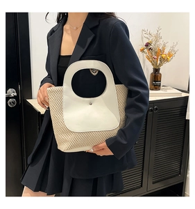 Detail of vintage patchwork straw handbag with round handle and contrast white paneling