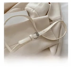 Detail of adjustable beige leather shoulder strap with silver buckle on a handbag