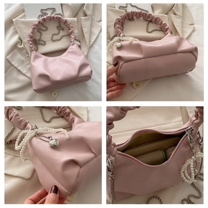 Close-up of pink pleated underarm bag with pearl chain and metal heart pendant