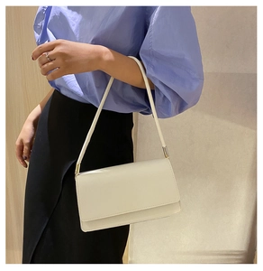 Detail shot of the white leather minimalist shoulder bag with elegant gold metal hardware