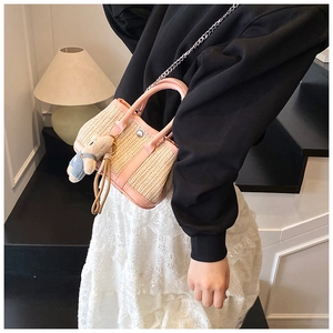 Detail of pink PU leather trim and straw woven texture on crossbody bag with bear charm