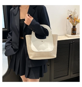 Detail of hand-woven straw tote with white leather trim and circular cutout handle