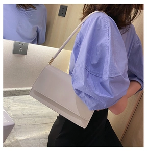 Close-up of a minimalist cream white leather shoulder bag with magnetic flap closure