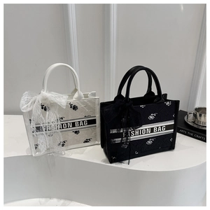 Detail of floral embossed tote bag with ribbon bow and fashion letter strap design