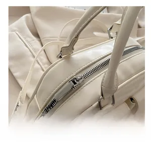 Detailed macro shot of smooth silver metal zipper on cream white leather pillow bag