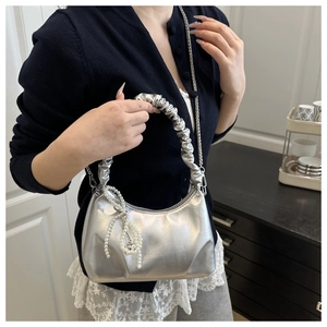 Detail of silver metallic cloud bag with scrunchie handle and pearl bow charm