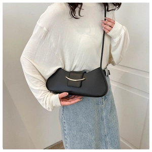 Vista dettagliata di una borsa sottobraccio nera minimalista indossata da una modella.