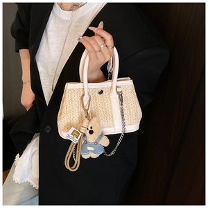 Detail of woven straw mini bag with pink leather trim and cute plush bear charm