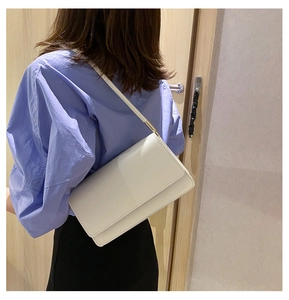 Detail of white lychee pattern leather shoulder bag with gold hardware on a model