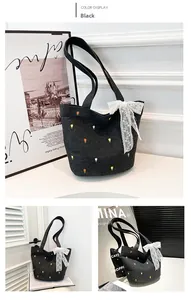 Detail of black denim tote bag with tulip embroidery and a white lace bow accent