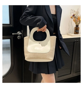 Detail of the straw and white leather patchwork handbag with a circular cutout handle