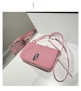 Detail view of pink crossbody bag featuring textured flap and silver rhinestone buckle