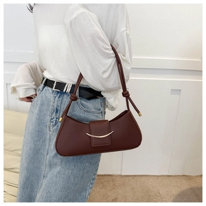 Modella indossa una borsa a spalla baguette marrone con dettagli in metallo dorato