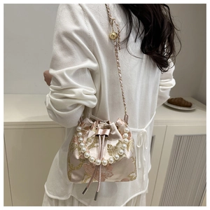 Macro shot of pink satin bucket bag with golden floral embroidery and pearl handle