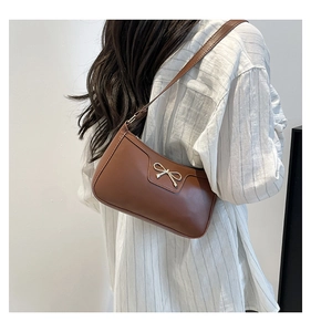 Rear view of model wearing a brown crescent underarm bag with gold bow detail