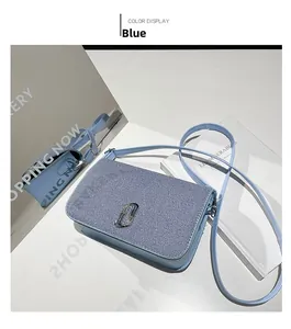 Detail of blue crossbody bag featuring denim texture cover and silver logo emblem
