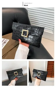 Detail of black glossy crocodile pattern envelope clutch with gold metal buckle