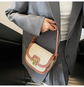 Detail of vintage canvas and leather saddle bag with contrast stitching and metal clasp