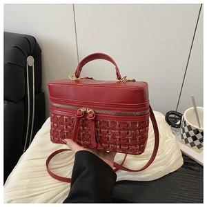 Detail of red tweed and leather box bag featuring a dual metal zipper and top handle