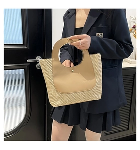 Close-up of woven straw tote bag featuring a gold metal clasp and faux leather handle