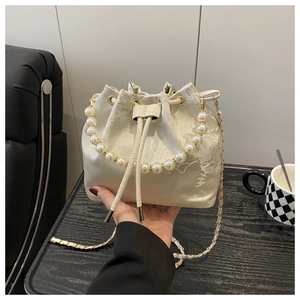 Close-up of cream bucket bag with white floral embroidery and faux pearl handle