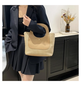 Close-up of contrast stitching straw bag with leather top and round cutout handle