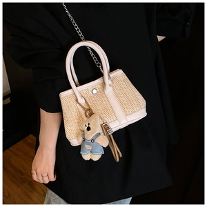 Detail of woven straw handbag with pink leather trim and cute teddy bear charm