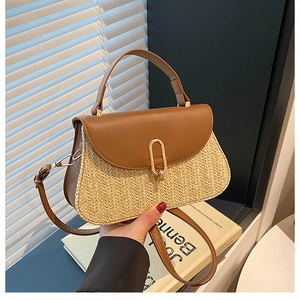 Detail of woven straw handbag with brown leather flap and golden oval metal clasp closure