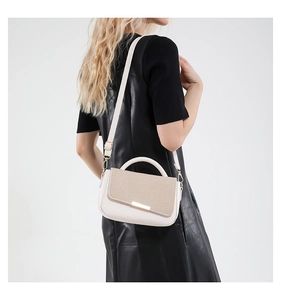 Dettaglio di una borsa a tracolla bianca con patta testurizzata indossata da una modella.