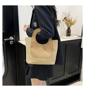Close-up of contrast woven straw tote bag featuring brown leather handles and detail