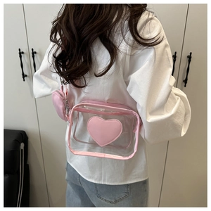 Detailed view of a pink transparent crossbody bag with heart patch worn by a model.
