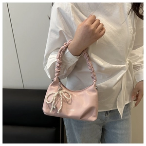 Pink shoulder bag detail showing pleated ruched handle and a pearl bow charm pendant