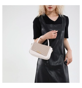 Elegante borsa beige con patta testurizzata tenuta da una modella in abito nero